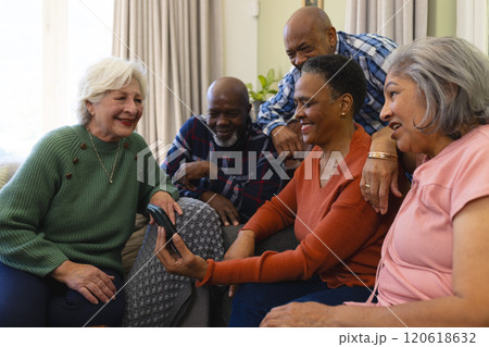 Happy diverse group of senior friends having video call and smiling in sunny living room Happy diverse group of senior friends having video call and smiling in sunny living room 120618632