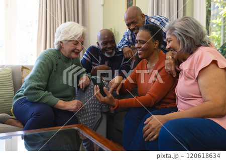 Happy diverse group of senior friends having video call and smiling in sunny living room 120618634