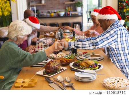 Happy diverse group of senior friends celebrating at christmas dinner in sunny dining room at home Happy diverse group of senior friends celebrating at christmas dinner in sunny dining room at home 120618715