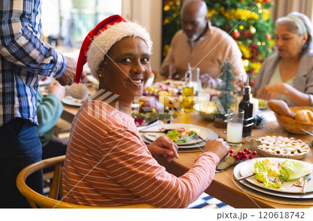 Happy african american senior woman celebrating with friends at christmas dinner in dining room 120618742
