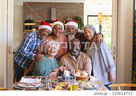 Happy diverse group of senior friends posing to picture at christmas dinner in sunny dining room 120618751