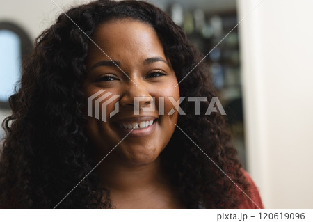 Head of happy african american woman with curly hair smiling in sunny house 120619096