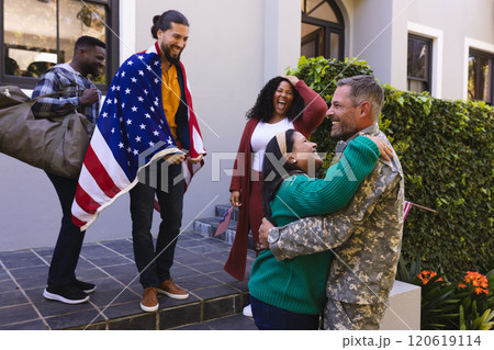 Happy diverse friends with flags welcoming home male soldier friend 120619114