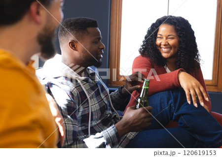 Happy diverse male and female friends talking and drinking beer at home 120619153