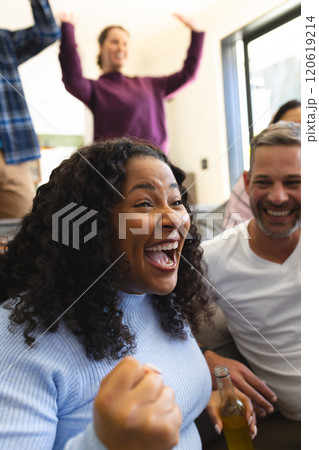 Excited diverse male and female friends watching sport on tv at home and drinking beers, copy space Excited diverse male and female friends watching sport on tv at home and drinking beers, copy space 120619214