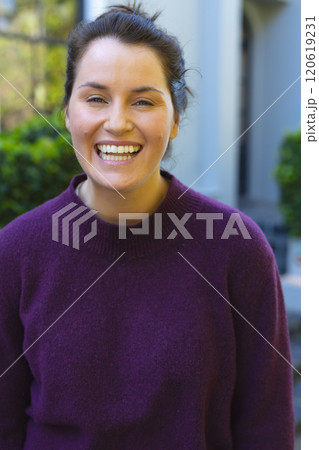 Portrait of happy caucasian woman standing and smiling in front of house in garden 120619231
