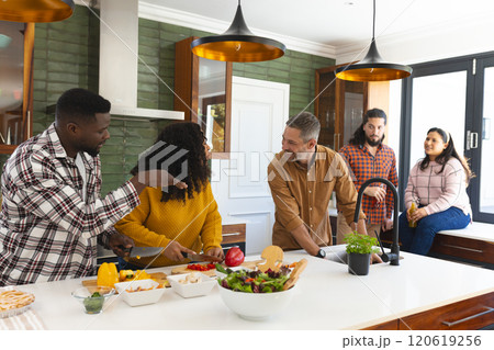 Happy diverse male and female friends preparing meal in kitchen Happy diverse male and female friends preparing meal in kitchen 120619256