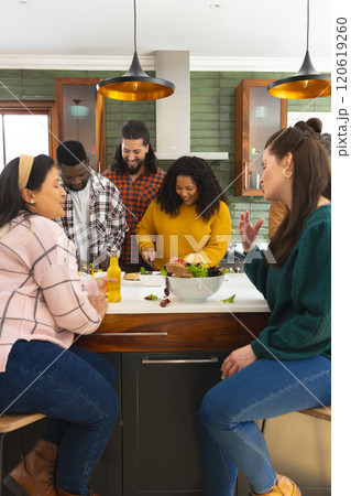 Happy diverse male and female friends preparing meal and drinking drinks in kitchen Happy diverse male and female friends preparing meal and drinking drinks in kitchen 120619260
