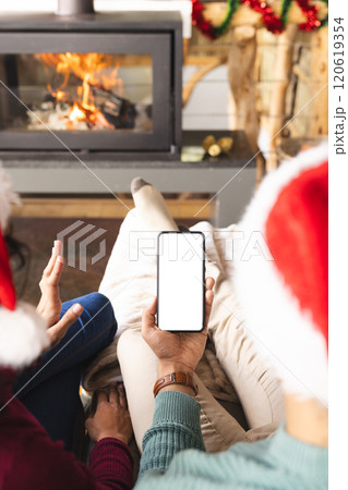 Biracial couple with santa hats having video call on smartphone at christmas at home, copy space 120619354