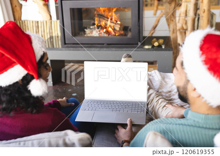 Biracial couple with santa hats having video call on laptop at christmas at home, copy space 120619355