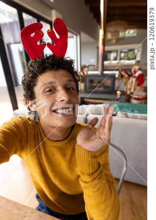 Portrait of happy biracial man wearing reindeer antlers and having video at christmas at home Portrait of happy biracial man wearing reindeer antlers and having video at christmas at home 120619379