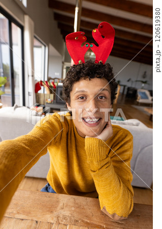 Portrait of happy biracial man wearing reindeer antlers and having video at christmas at home Portrait of happy biracial man wearing reindeer antlers and having video at christmas at home 120619380
