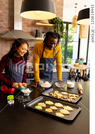 Happy diverse couple admiring freshly baked christmas cookies in kitchen, copy space Happy diverse couple admiring freshly baked christmas cookies in kitchen, copy space 120619443