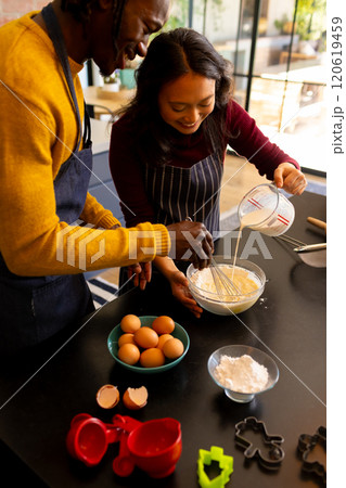 Happy diverse couple baking christmas cookies mixing dough in kitchen, copy space 120619459