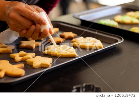 Hands of asian woman decorating christmas cookies with icing in kitchen, copy space Hands of asian woman decorating christmas cookies with icing in kitchen, copy space 120619472
