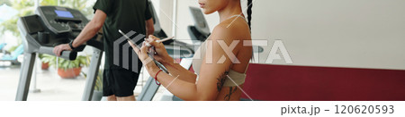 Woman Monitoring Workout Sessions at Gym 120620593