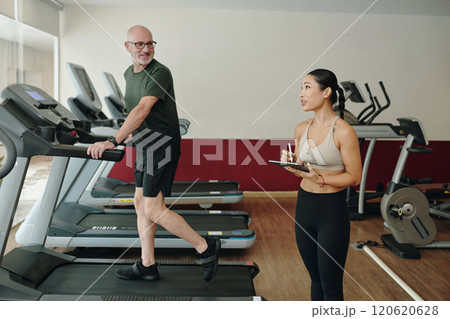 Discussing Fitness Goals While Exercising on Treadmill Discussing Fitness Goals While Exercising on Treadmill 120620628