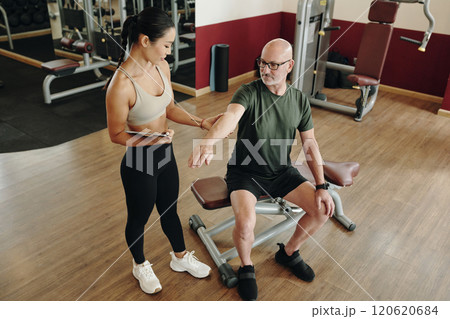 Senior Man Receiving Personal Training at Gym 120620684