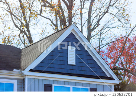 Reveals elegant design of gray house highlighting shingles on roof surrounding, unique architectural details 120622701