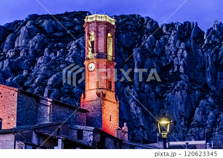 Views of the illuminated Church of Sant Corneli in Collbato, Barcelona at dusk, with the Montserrat mountain in the background 120623345