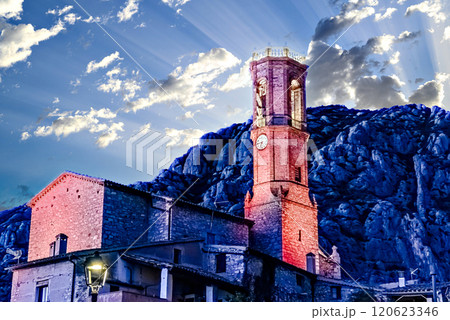 Views of the illuminated Church of Sant Corneli in Collbato, Barcelona at dusk, with the Montserrat mountain in the background 120623346