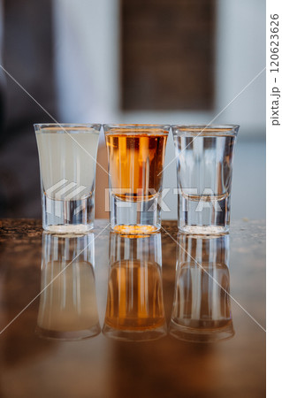 Three glasses of diverse drinks reflecting on a shiny surface for a modern beverage concept Three glasses of diverse drinks reflecting on a shiny surface for a modern beverage concept 120623626