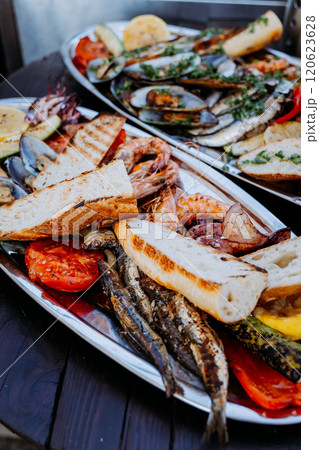 Grilled seafood feast with fresh bread and vegetables served on a platter for outdoor dining 120623628