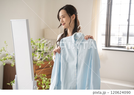 屋内で服を選ぶ若い女性 120624090