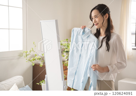屋内で服を選ぶ若い女性 120624091