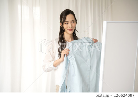 屋内で服を選ぶ若い女性 120624097