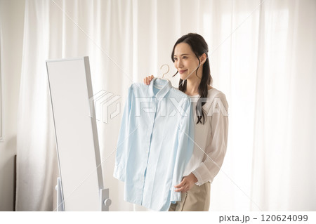 屋内で服を選ぶ若い女性 120624099