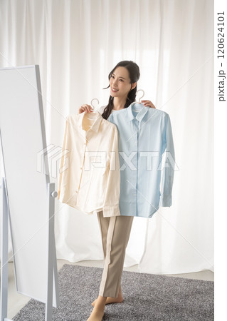 屋内で服を選ぶ若い女性 120624101