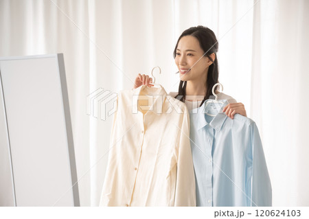 屋内で服を選ぶ若い女性 120624103