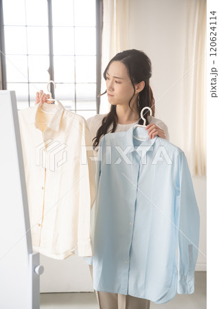 屋内で服を選ぶ若い女性 120624114
