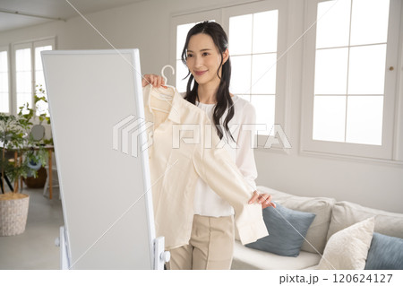 屋内で服を選ぶ若い女性 120624127