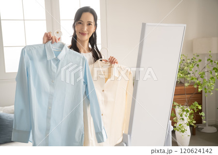屋内で服を選ぶ若い女性 120624142