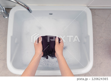Handwashing violet clothes in a sink filled with soapy water, highlighting a simple and effective laundry routine. Handwashing violet clothes in a sink filled with soapy water, highlighting a simple and effective laundry routine. 120624365