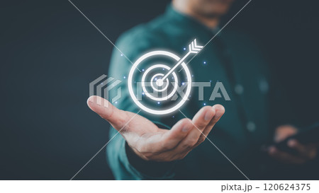 A businessman holds a glowing digital target with an arrow in the center, symbolizing focus and goal achievement. The futuristic design highlights innovation and success. A businessman holds a glowing digital target with an arrow in the center, symbolizing focus and goal achievement. The futuristic design highlights innovation and success. 120624375