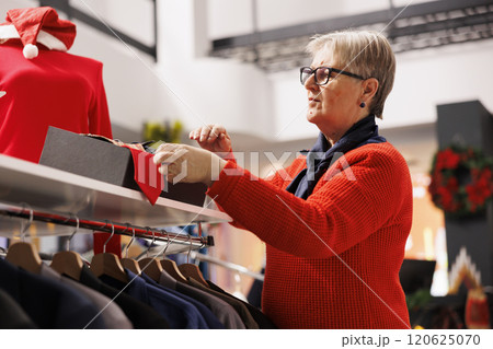 Buyer checking box of items in retail store, searching for ties and belts as presents for festive christmas dinner. Old person searching for clothes on hangers and accessories, winter sales. 120625070
