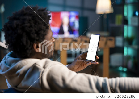 Man texting internet mates using mockup mobile phone at home, having fun. Joyful person relaxing in apartment by scrolling on isolated screen smartphone, entranced by social media activity Man texting internet mates using mockup mobile phone at home, having fun. Joyful person relaxing in apartment by scrolling on isolated screen smartphone, entranced by social media activity 120625296