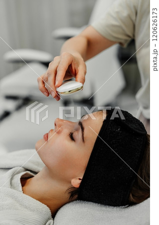 Woman receiving a facial treatment in a serene spa setting during the afternoon 120626173
