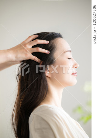 目を閉じるヘッドマッサージやヘッドスパなどをするイメージ のクローズアップ	縦 120627306