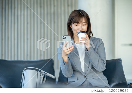 スマホを見るOL　空港のロビーで誰かを待つ女性　OL　働くオフィスレディ 120629083