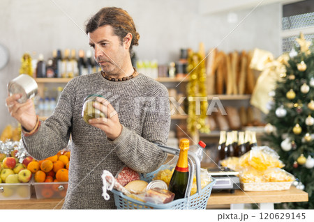 Man choosing preserves for festive grocery basket on Christmas Eve 120629145