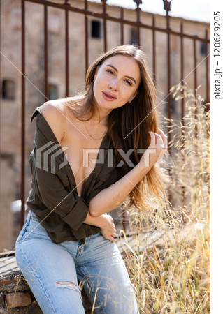 Woman in unbuttoned blouse posing near fence 120629205