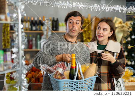Cheerful couple shopping for Christmas dinner wine and goodies Cheerful couple shopping for Christmas dinner wine and goodies 120629221