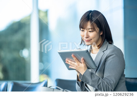 タブレットPCを見るOL　空港のロビーで誰かを待つ女性　OL　働くオフィスレディ 120629236