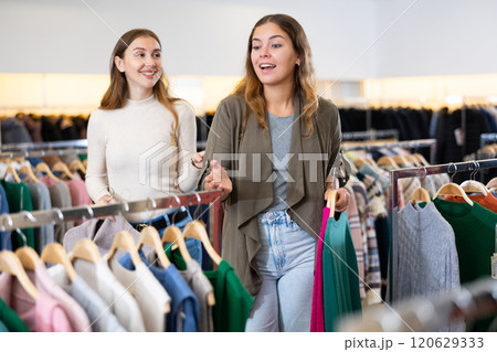 Shopping room of clothing shop with young women choosing jackets and sweater 120629333