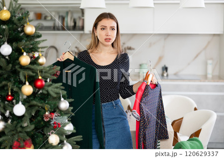 Upset indecisive woman can choose dress in her wardrobe for Christmas celebration Upset indecisive woman can choose dress in her wardrobe for Christmas celebration 120629337