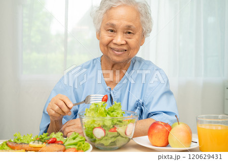 Asian elderly woman patient eating salmon steak breakfast with vegetable healthy food in hospital. 120629431